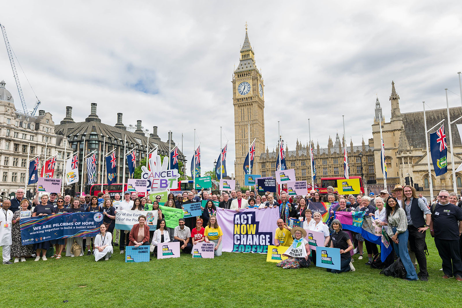 Image shows a group of people with banners in front of the Houses of Parliament